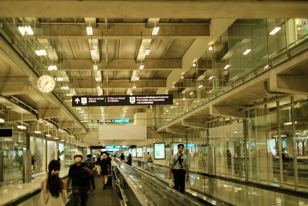 Passengers walking in a well-lit modern airport terminal with glass design.